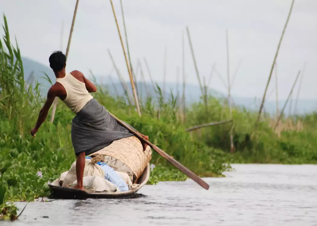 A leg rower transports his goods on one of the channels to Inle Lake
