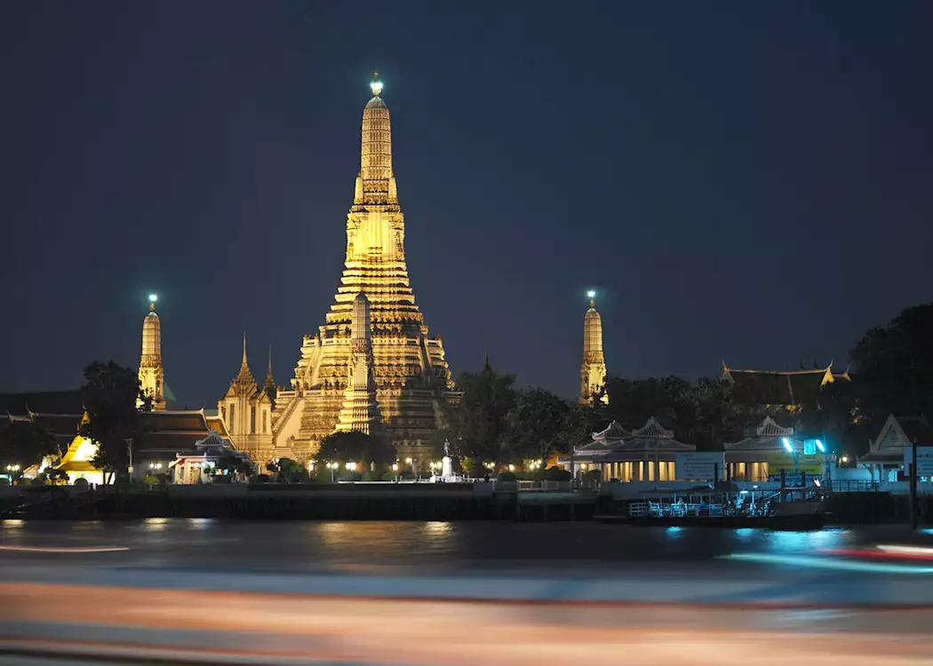 Wat Arun shines brightly alongside the Chao Phraya River, Bangkok, Thailand