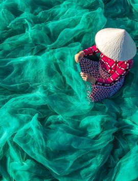 Fisherman repairing nets in Hoi An