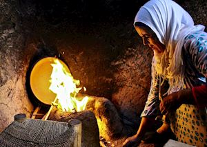A Berber woman stokes the fire before making mint tea