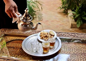 A woman pours sweet mint tea for guests of La Mamounia