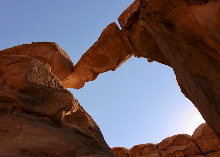 Desert sky over looming, sandstone, rock bridge