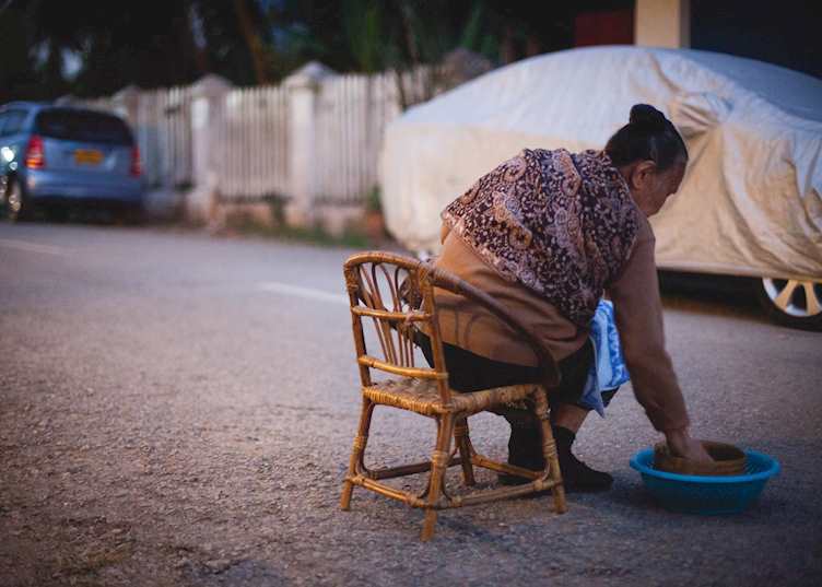 Woman giving alms before sunrise in Luang Prabang
