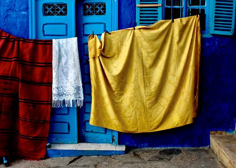 Fabrics hung to dry outside a blue painted dar