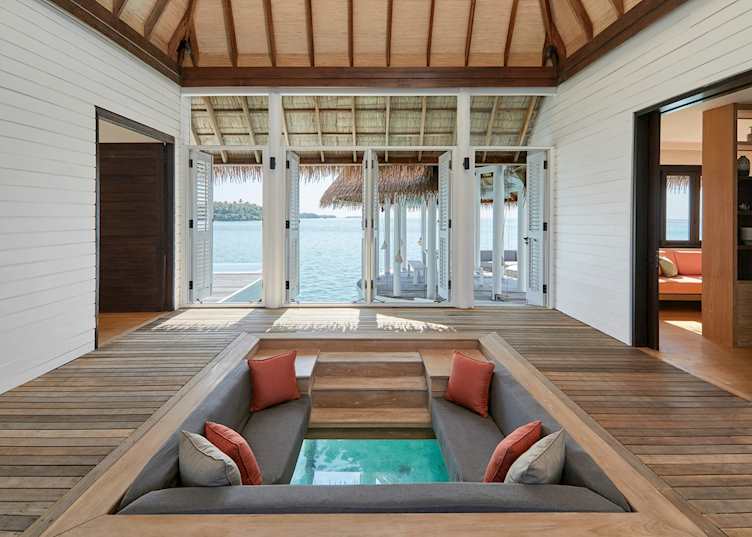The glass floor seating area of a water villa at COMO Maalifushi