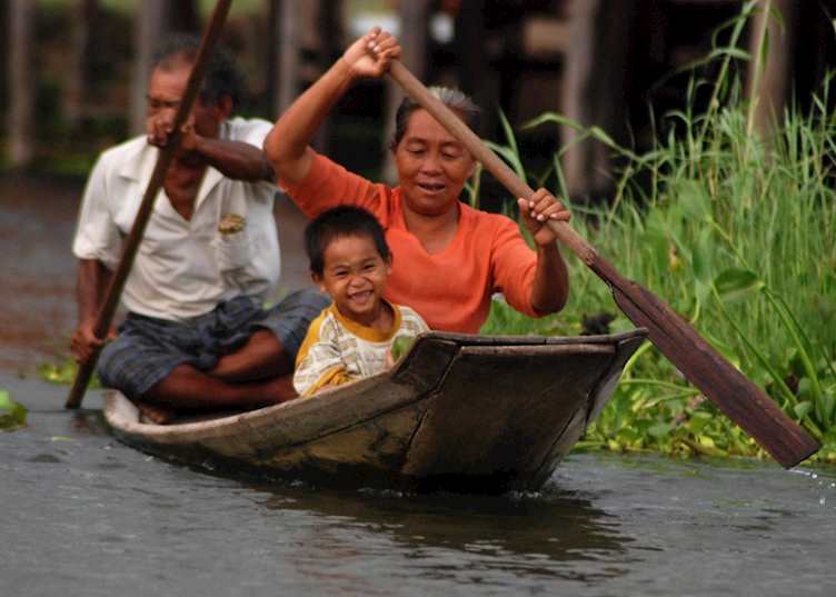 A child finds a funny moment as his family row him along Inle Lake