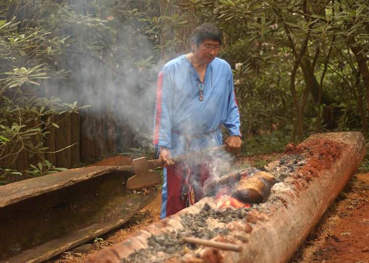 A Cherokee Native American making a traditional canoe