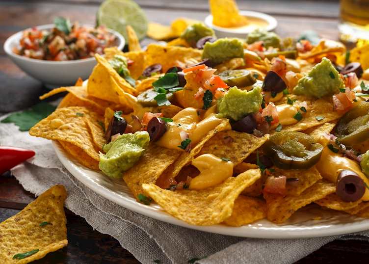 Mexican tortilla chips with olives, jalapeno, guacamole and tomatoes salsa