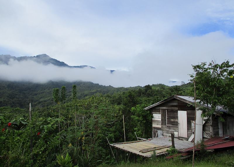 A village house in Kampong Nyegol with mist rising over the mountains
