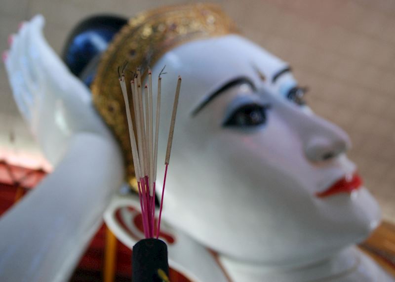 Incense sticks burn below the enormous reclining Buddha in Yangon