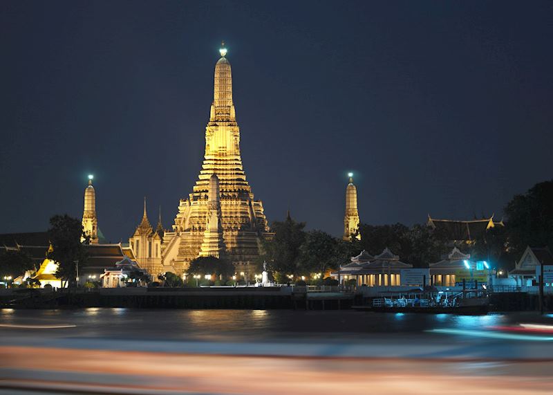 Wat Arun shines brightly alongside the Chao Phraya River, Bangkok, Thailand